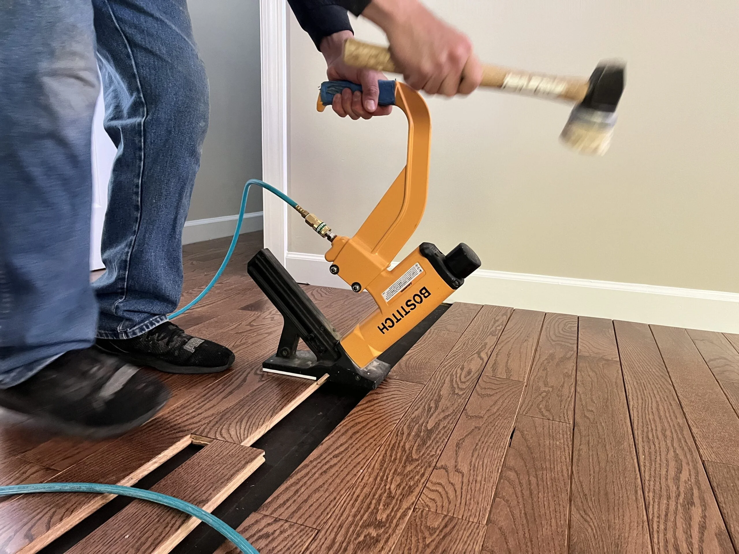 Hardwood flooring installation using a pneumatic flooring nailer and hammer